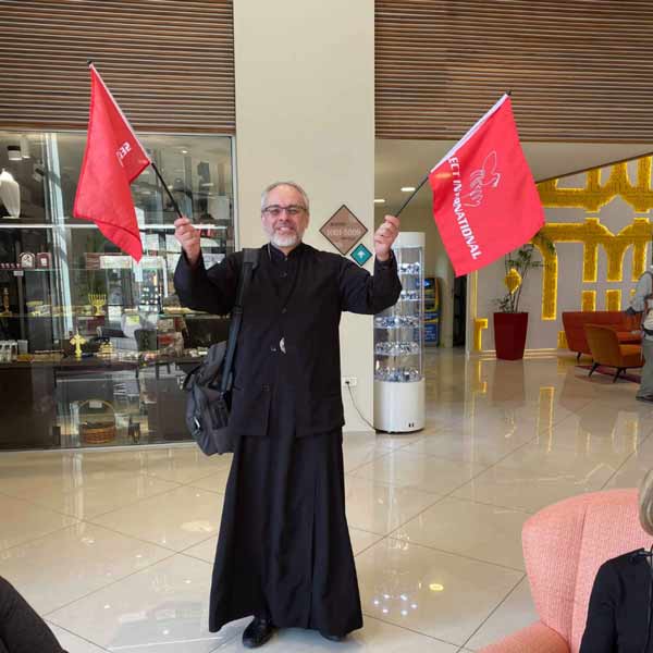 Priest with Select International Tours Flags